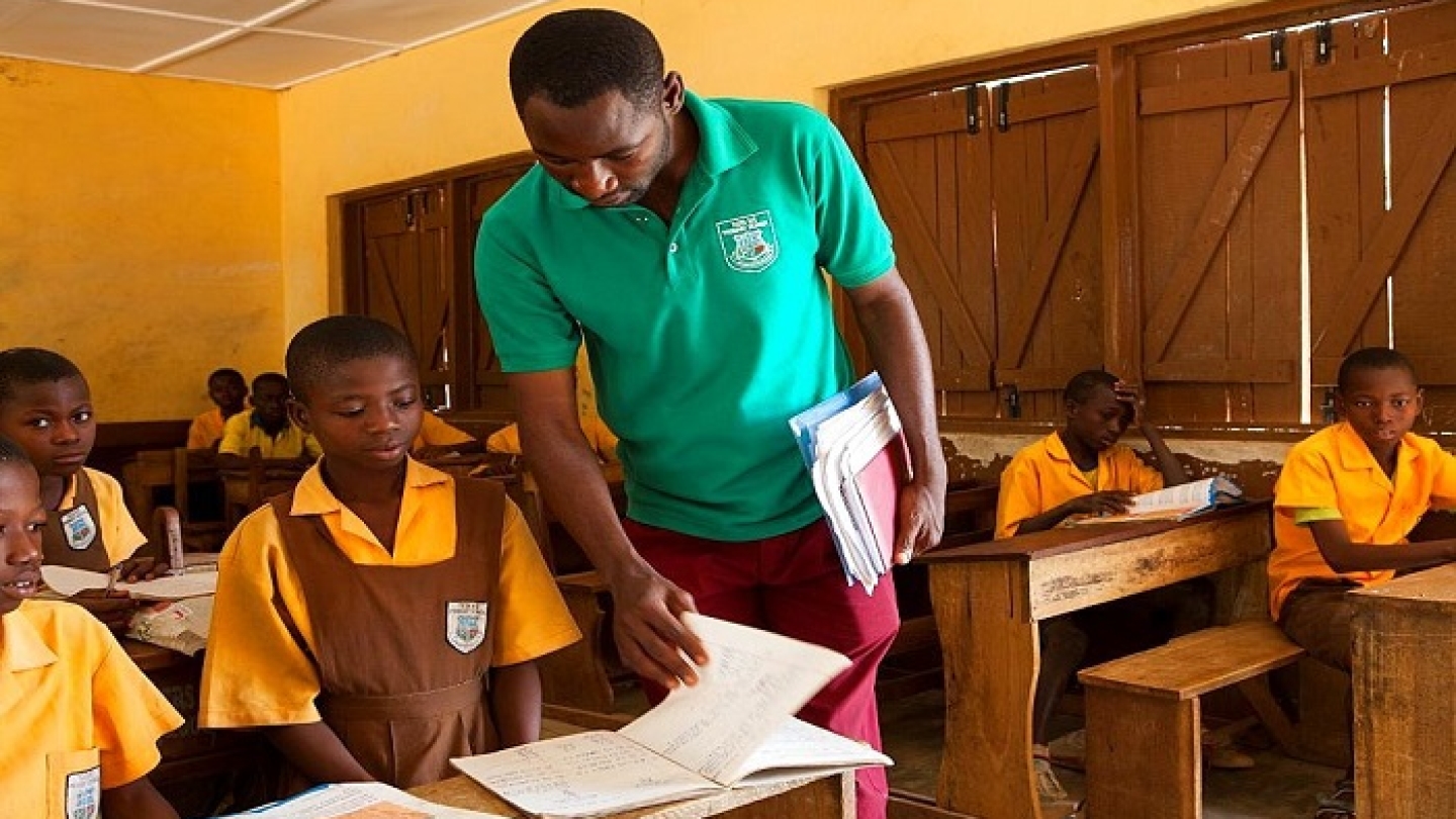 A male teacher teaching a classroom of children at a primary school in Ghana.