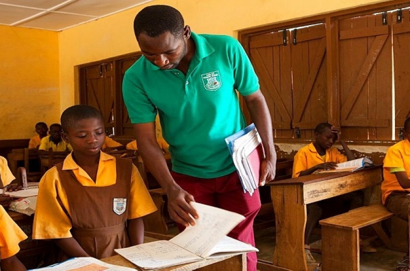 A male teacher teaching a classroom of children at a primary school in Ghana.