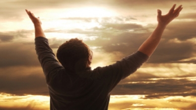 Man holding arms up in praise against golden sunset