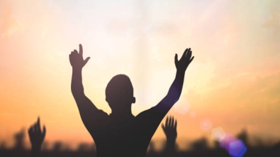 Silhouette christian people hand rising over blurred cross on spiritual light background