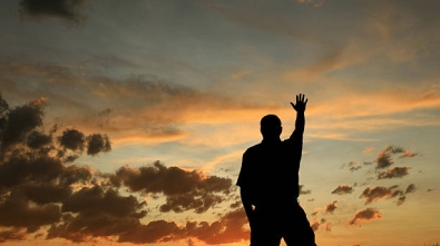 A man lifts his hand in worship. Silhouette.